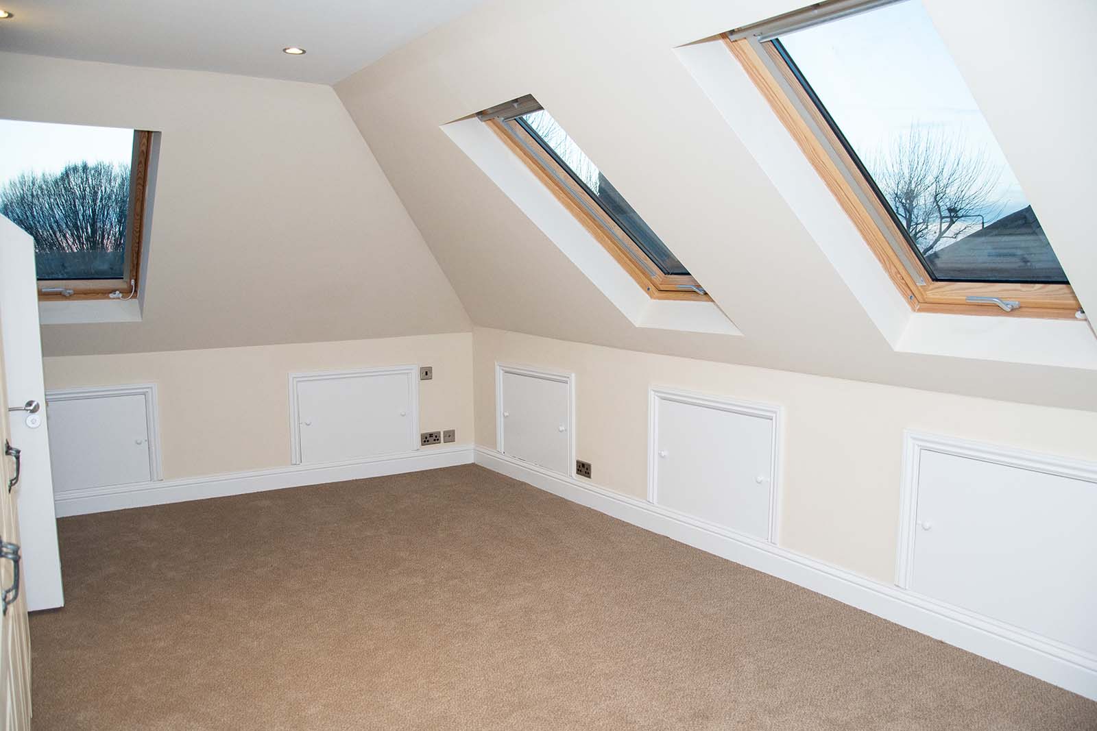 Carpeted loft room with 3 windows and and slanted walls
