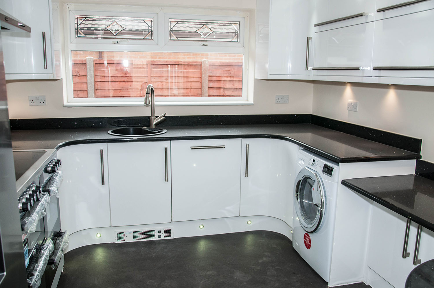 White kitchen with black countertops and one window